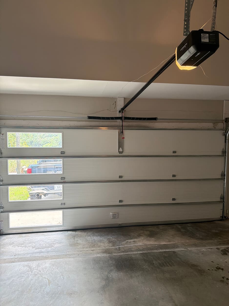 Inside view of a garage door with a column of glass panels and an opener overhead