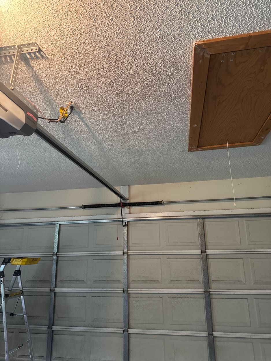 New torsion spring installed above a white sectional garage door