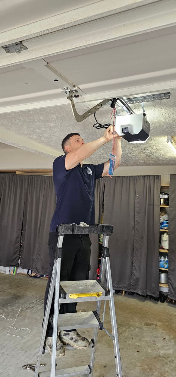 Swift Lift technician on a ladder installing a new garage door opener