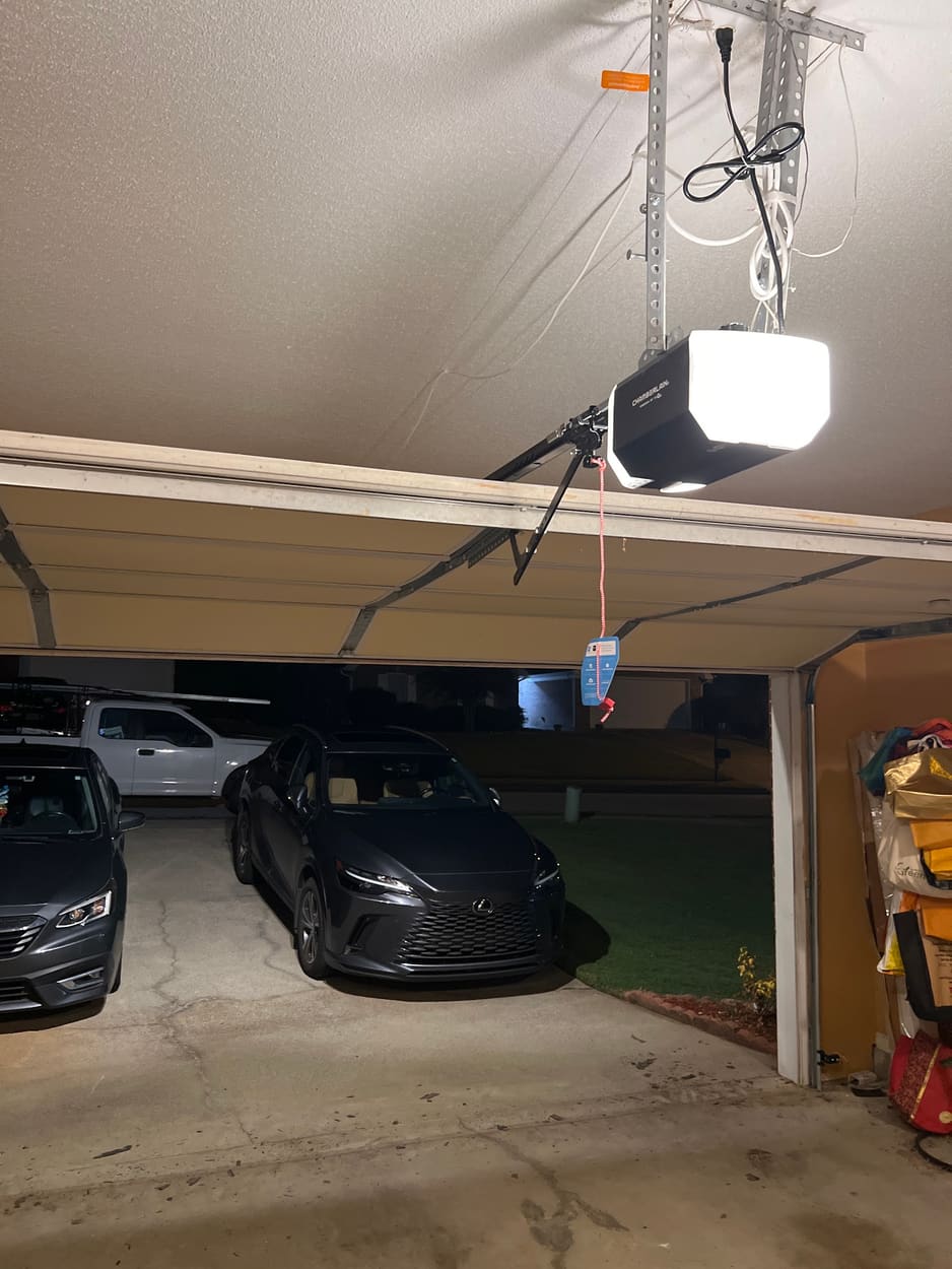 Garage door opener lit above an open garage door at night
