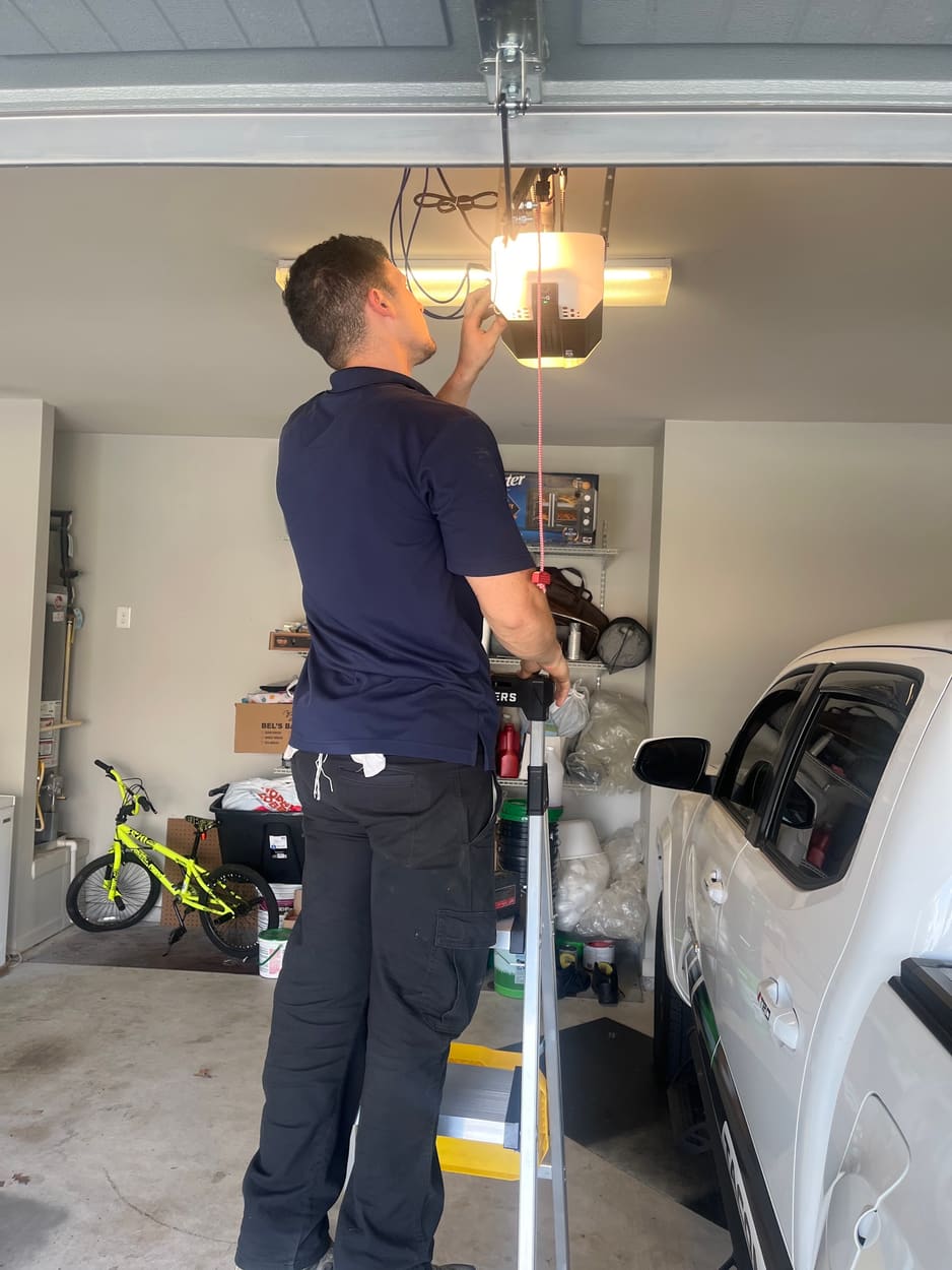 Swift Lift technician on a ladder adjusting a garage door opener
