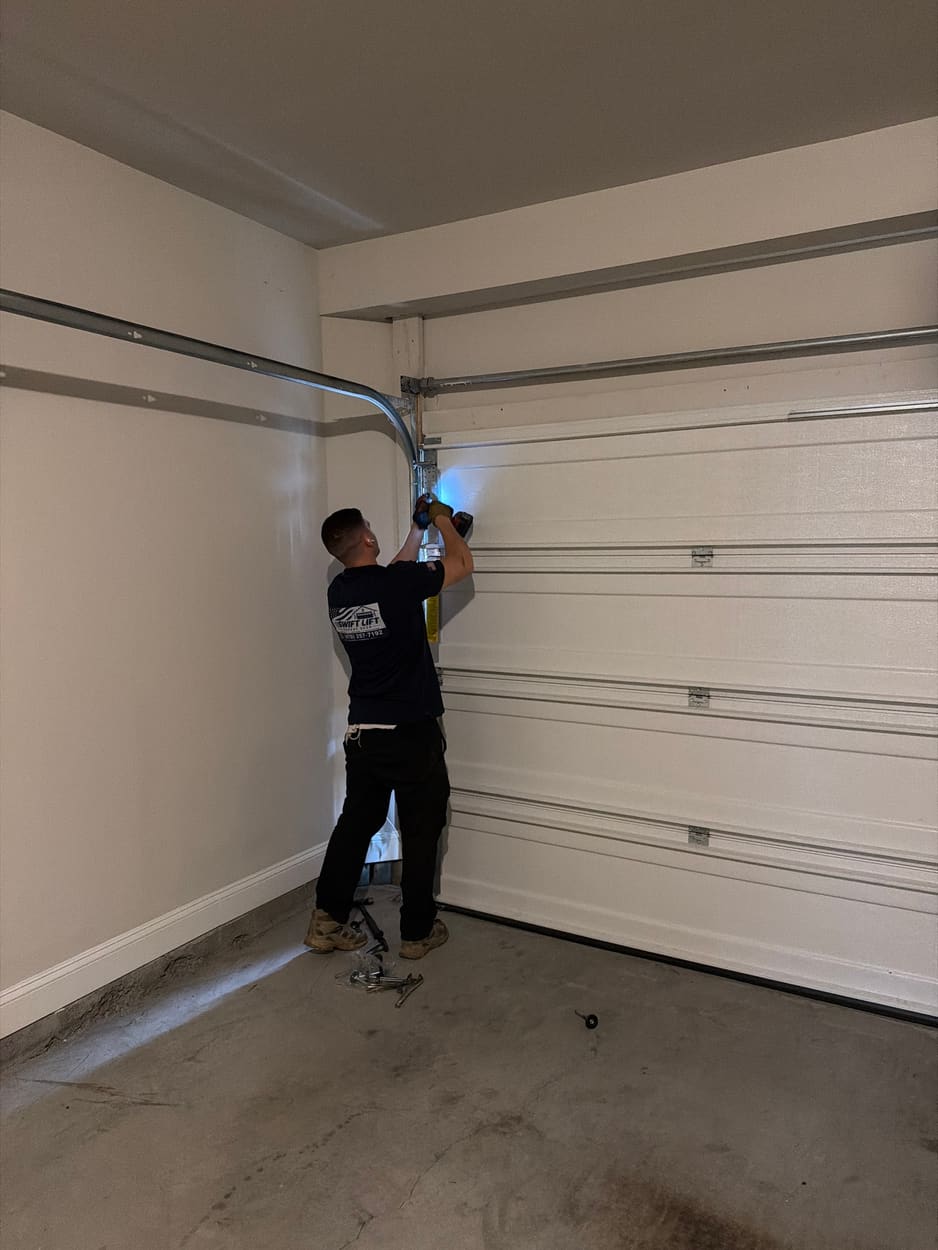 Swift Lift technician working on the track and rollers at the side of a white garage door