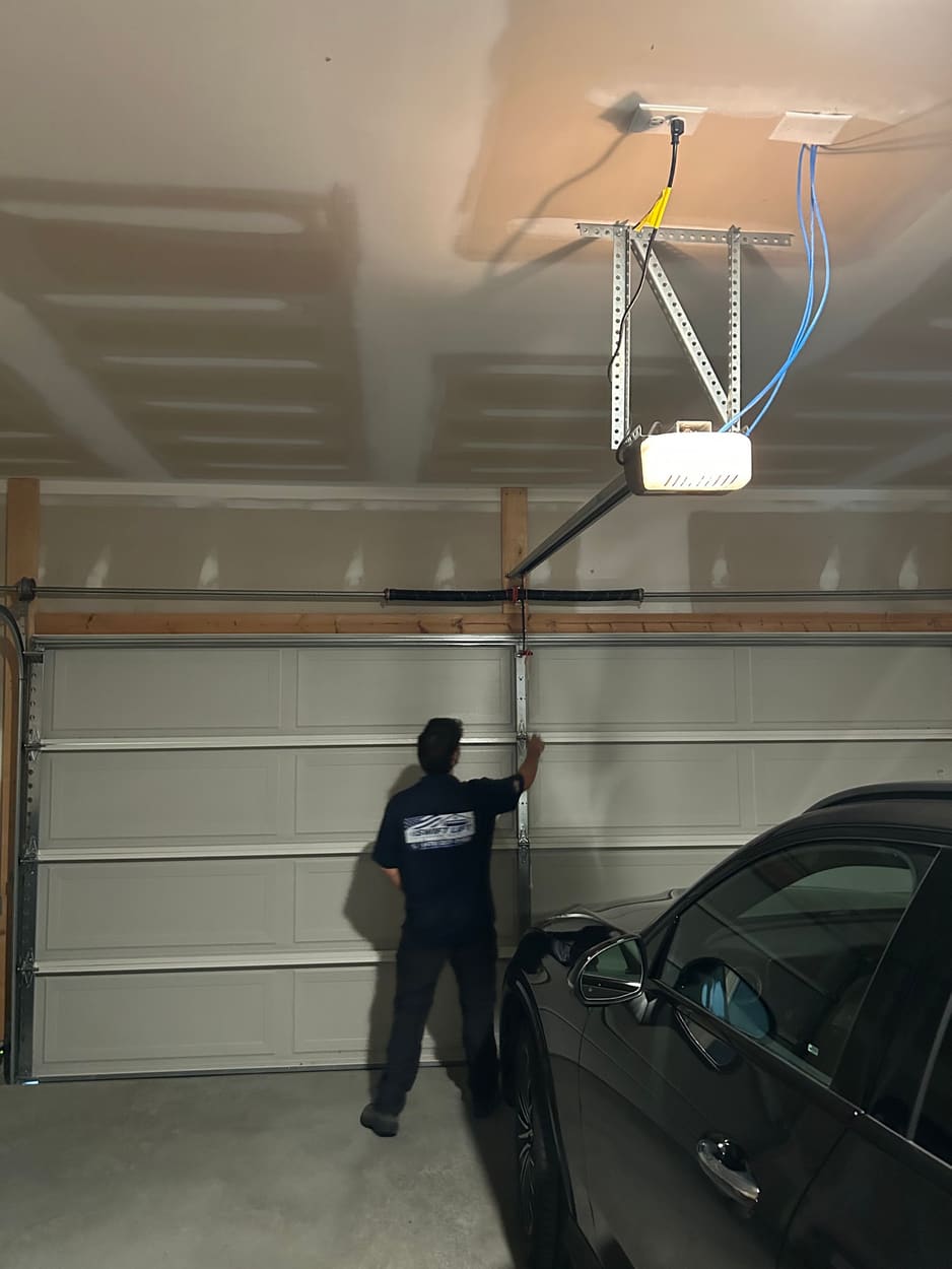 Swift Lift technician checking a garage door from inside the garage with an opener overhead