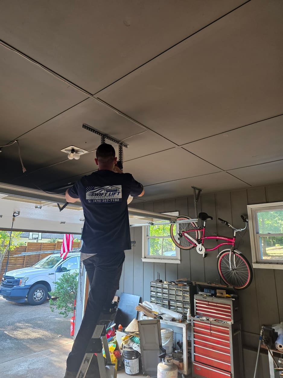 Swift Lift technician on a ladder servicing the spring bar in a customer's garage