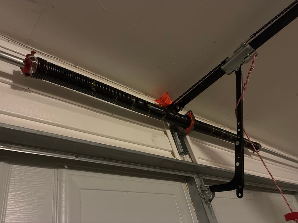 New torsion spring with winding cone and center bracket installed above a garage door