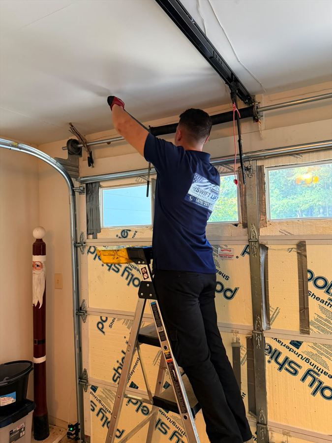 Swift Lift technician fitting the opener rail above a newly installed sectional garage door