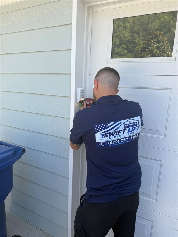 SwiftLift technician installing an exterior keypad beside a residential garage door