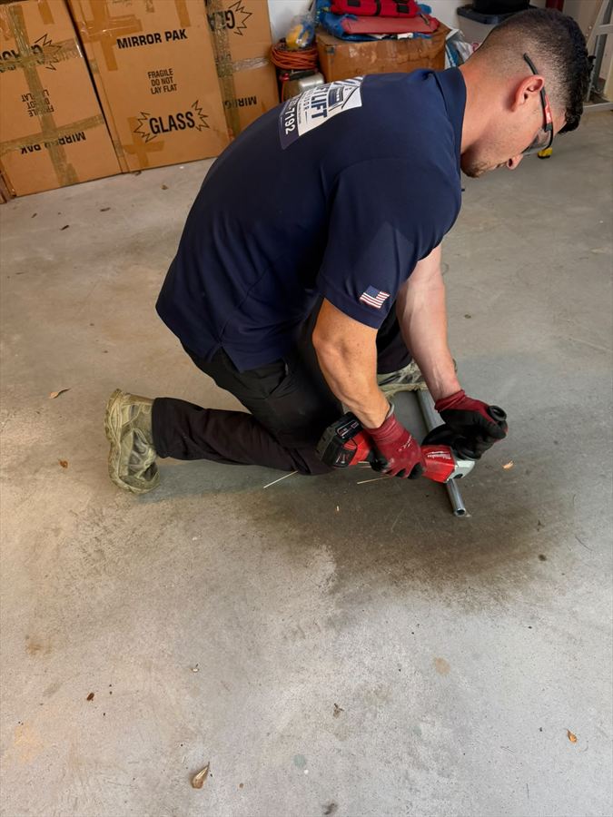 Swift Lift technician cutting a garage door torsion shaft to length with a cordless grinder